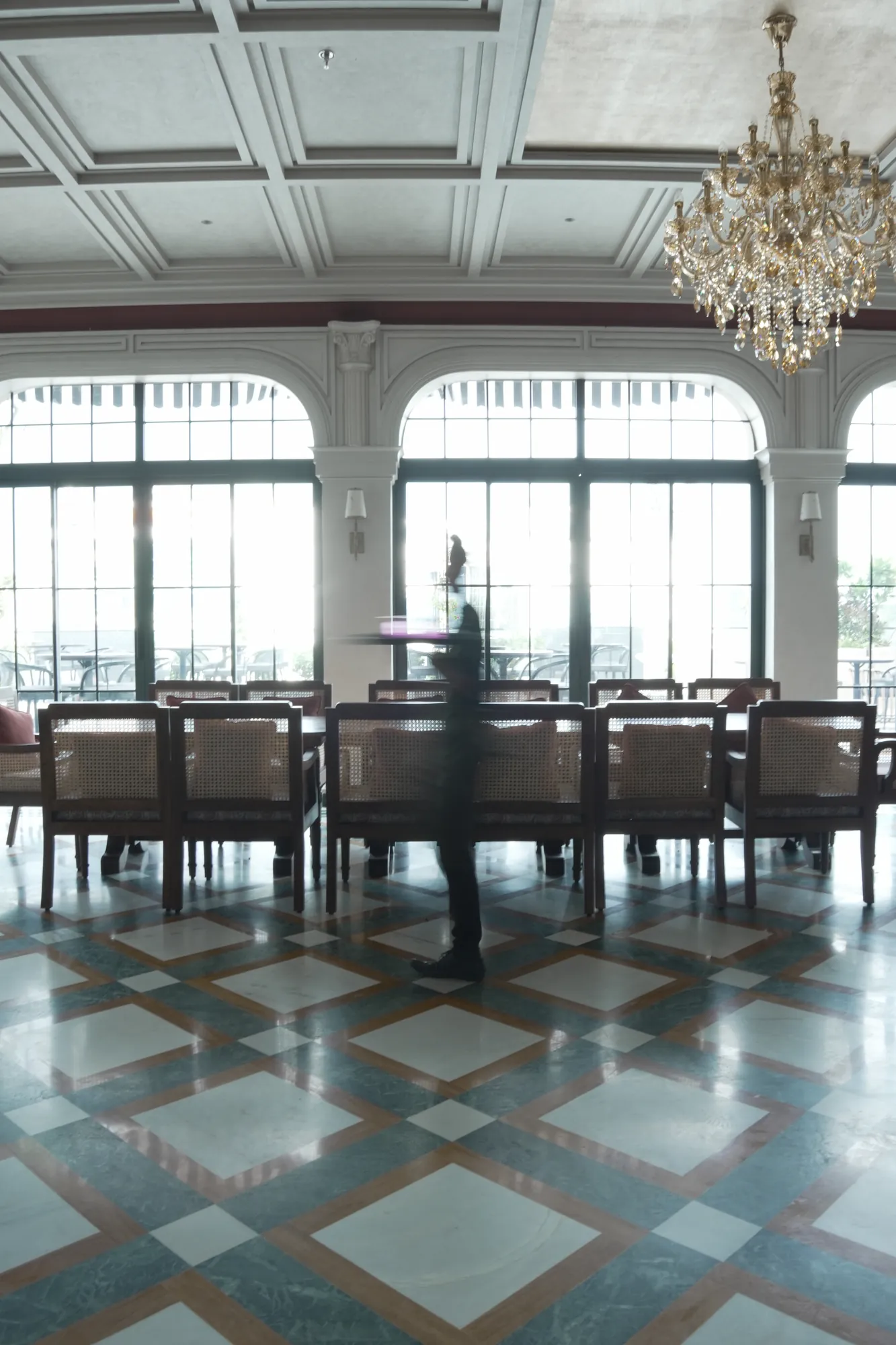 The long table beneath a crystal chandelier and arched windows