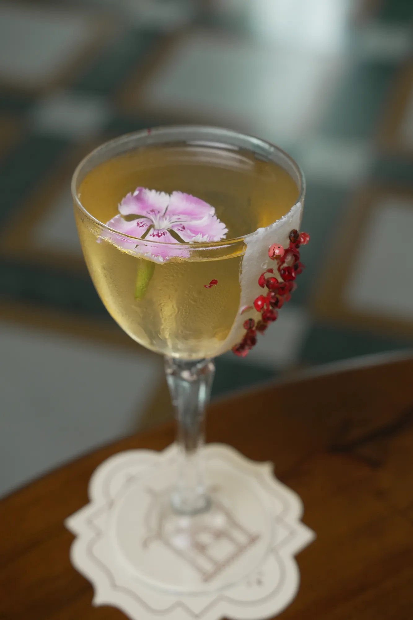 A clear signature cocktail with a single pink bloom