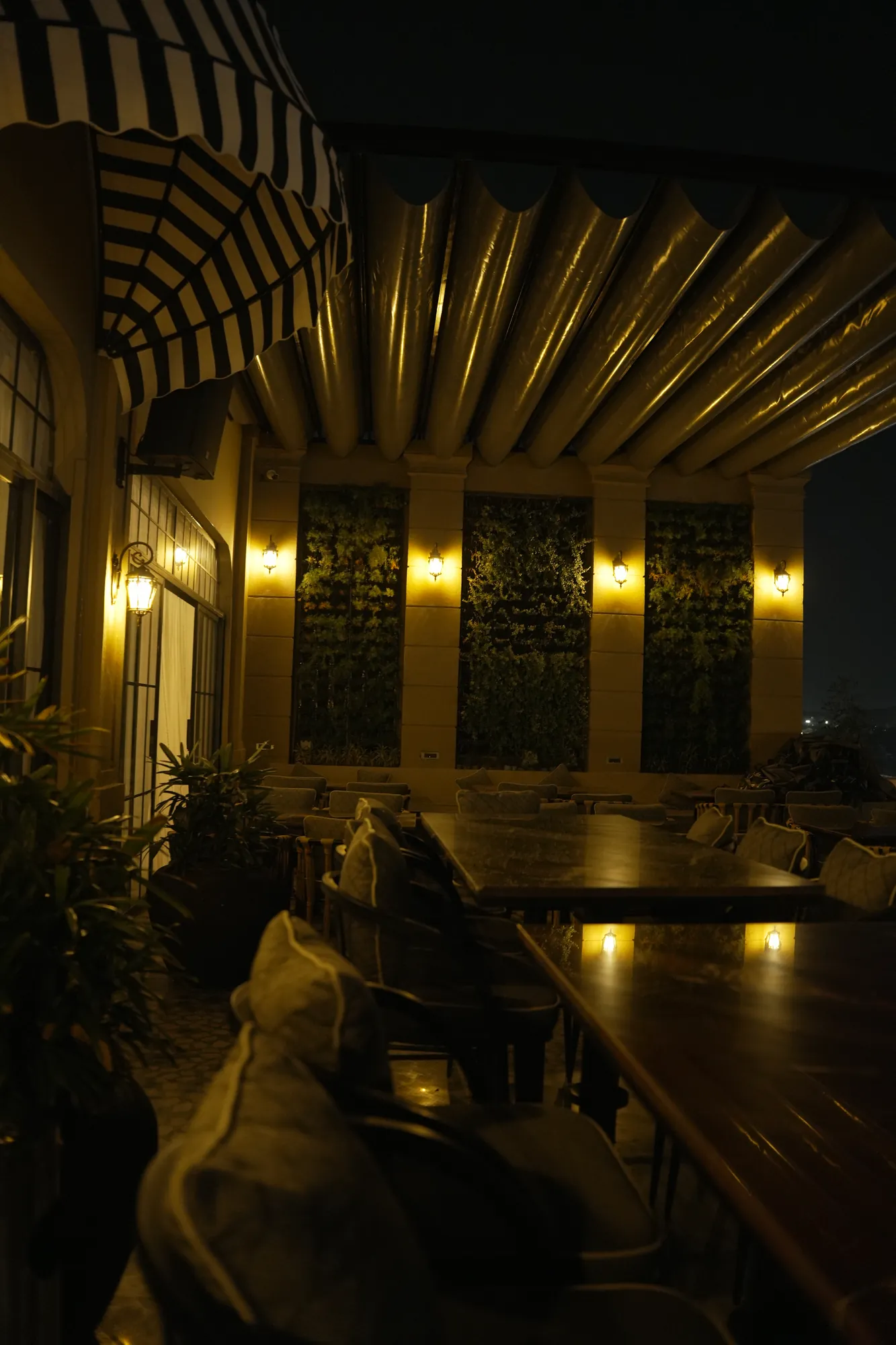 Brass wall lights and striped awnings along the terrace bar