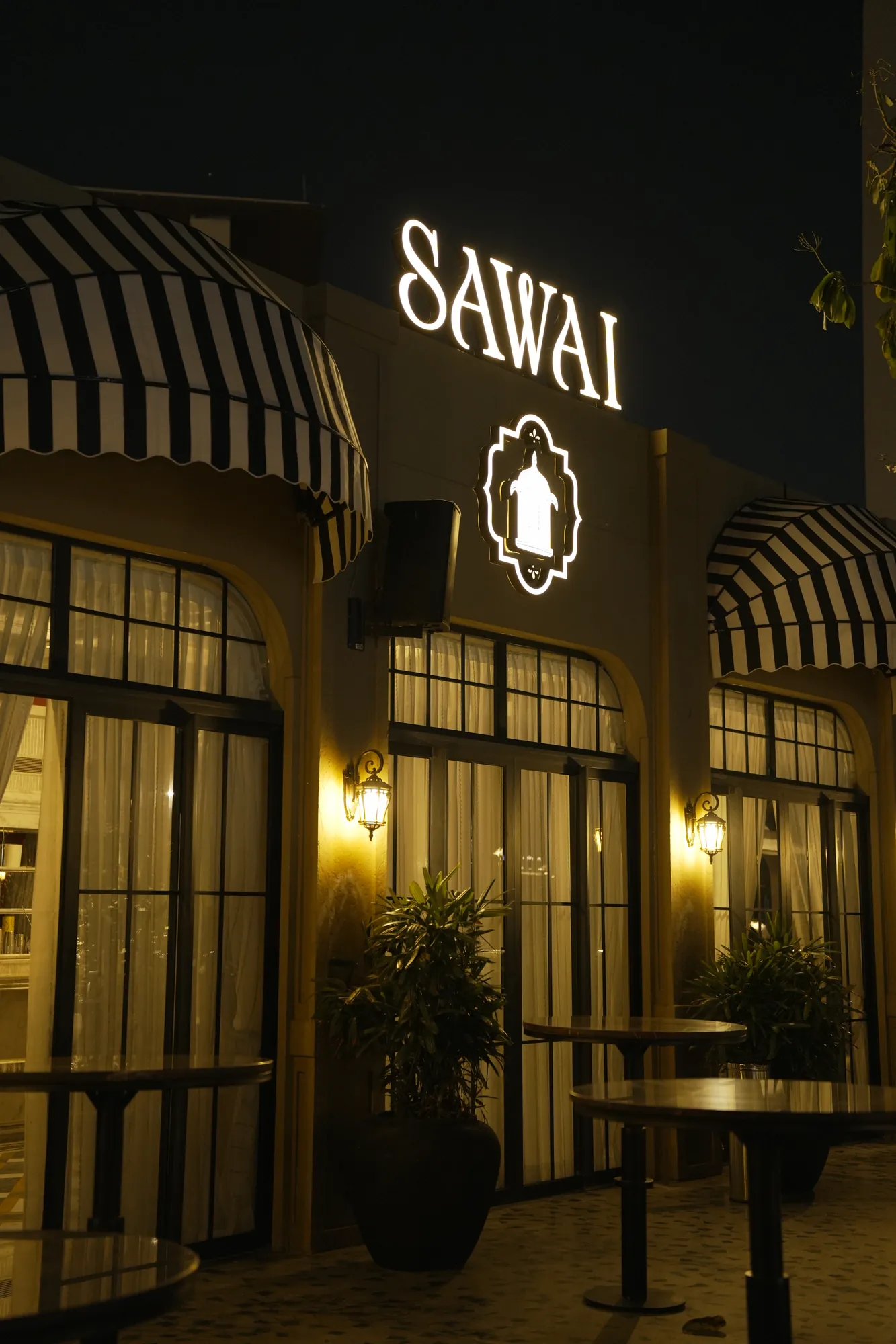 The lit SAWAI sign above striped awnings and lantern-lit doors