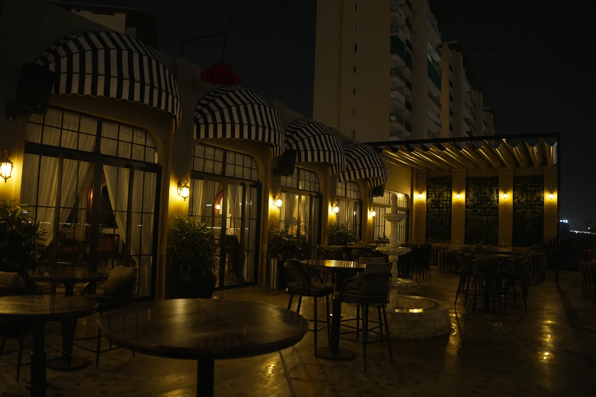 The Sawai's terrace at night — striped awnings, lantern-lit doors and tables under the open sky