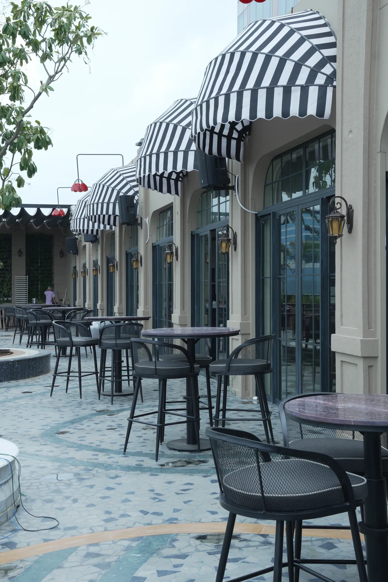 The terrace by day — black-and-white awnings and bistro tables